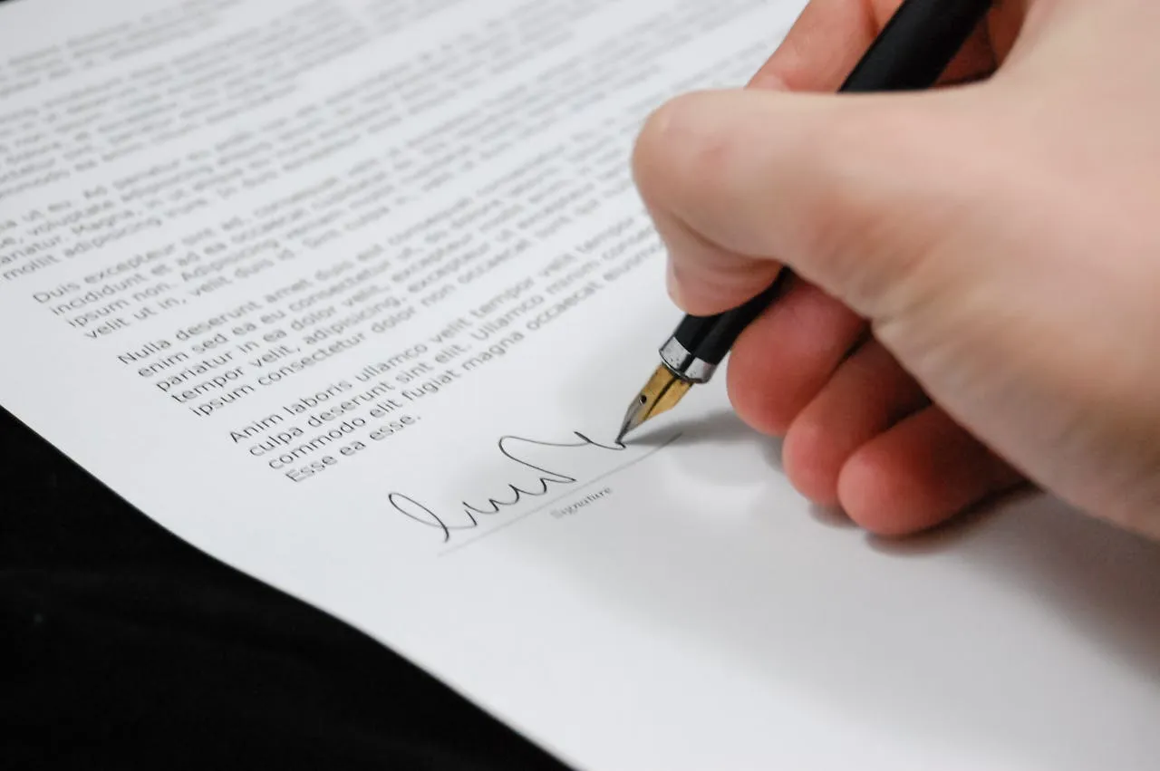 Main signant un contrat symbolisant un investissement financier dans un projet avec Finarma